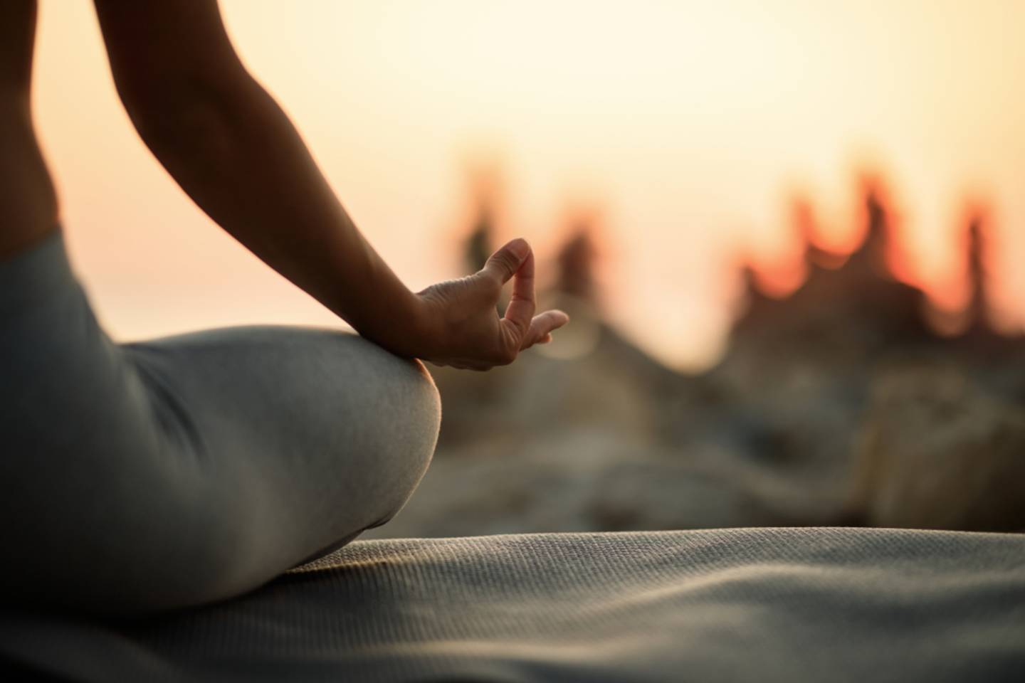 woman sitting with hand on knee, sunrise yoga