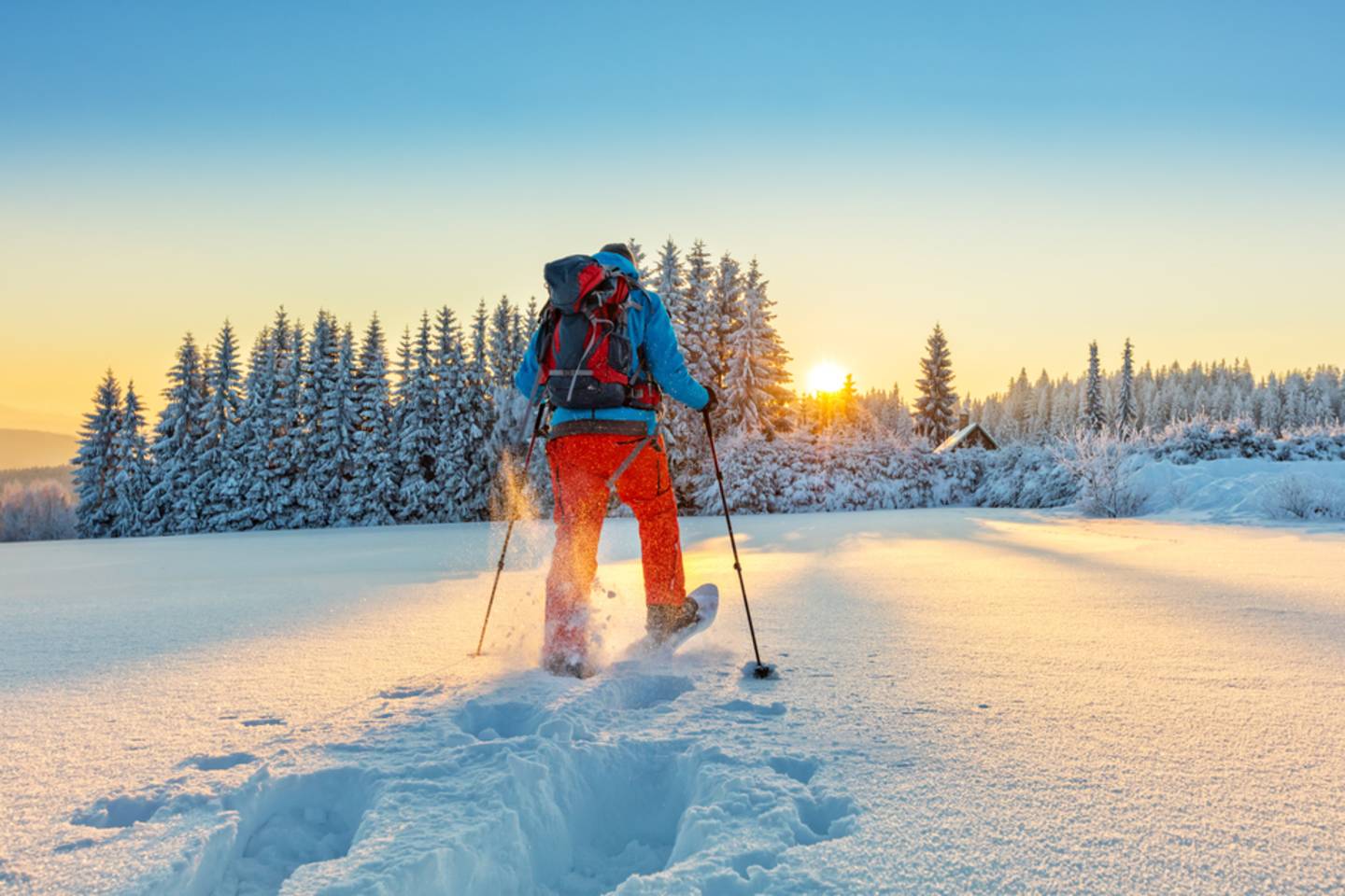 one person snowshoeing towards sunset